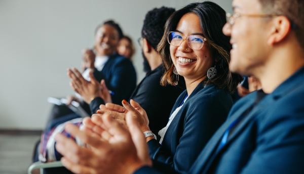 A woman is sitting and clapping her hands, expressing joy and enthusiasm.