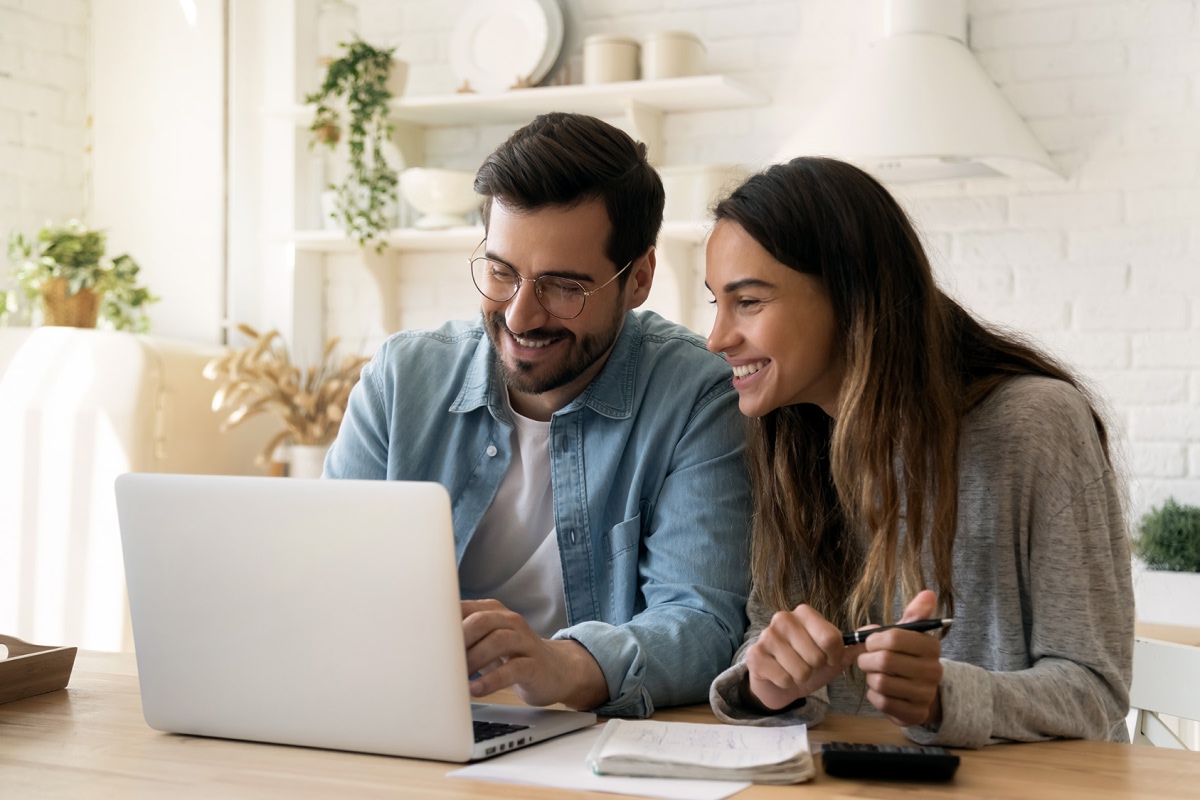 Man and woman smiling at their laptop.