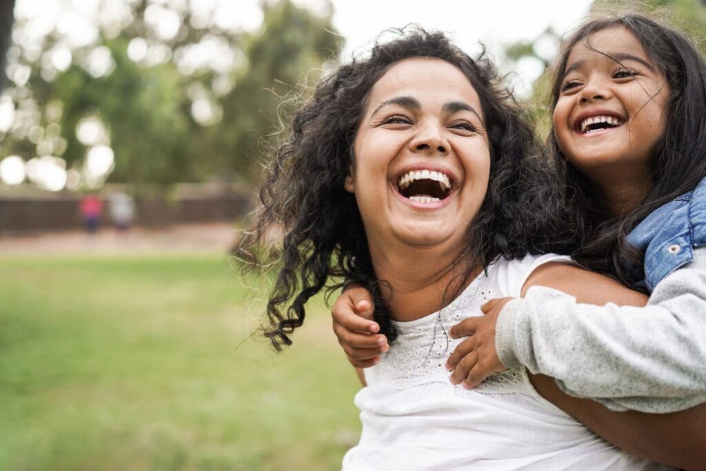 Little girl on a woman's back, both smiling.