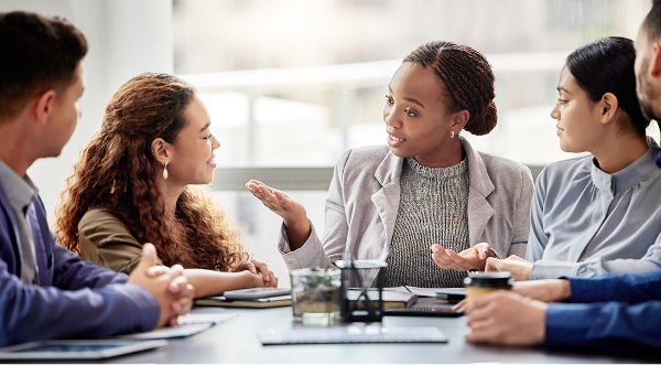 Woman talking at a desk with several different people.