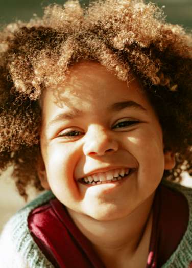 Little kid smiling with a joyful expression.